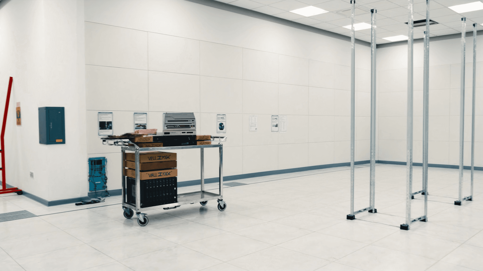 A bright data centre white space with empty open racks and an equipment trolley ready for installation