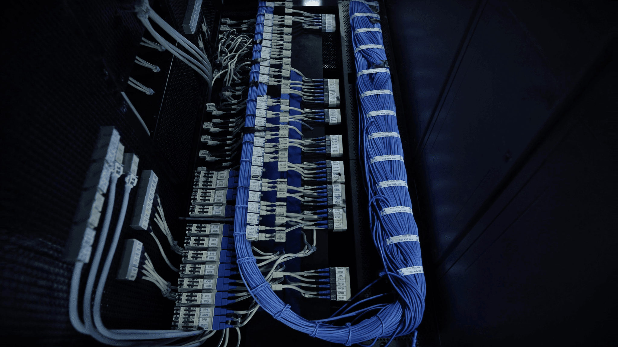 Rows of data centre cabinets with neatly dressed cabling visible through open doors, overhead cable trays above